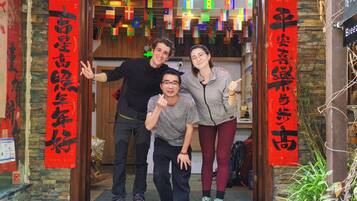 A group of people posing in front of a hotel entrance with red banners and a wooden interior.