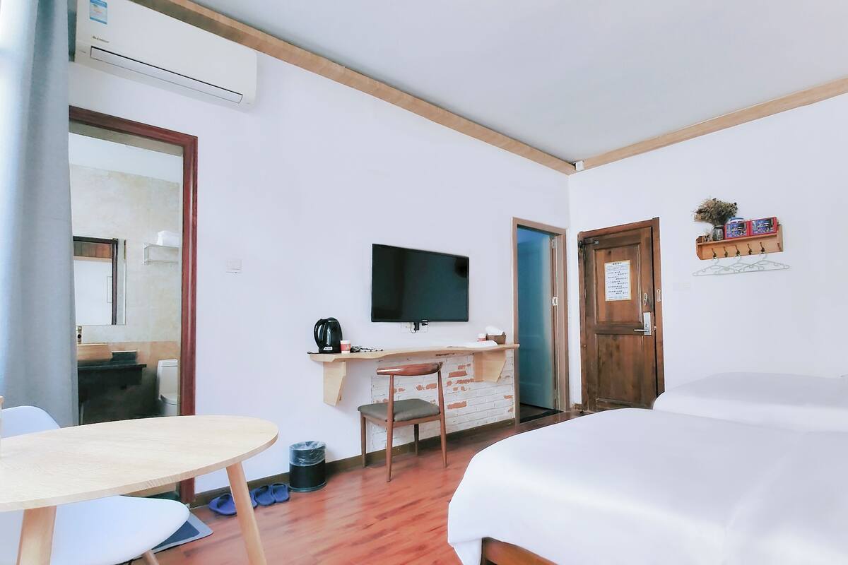 A hotel room with a bed, a desk with a chair, a television, and a small table.
