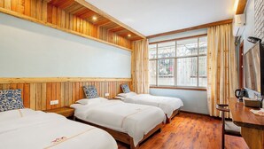 Een hotelkamer met houten lambrisering, twee bedden, een houten bureau en een groot raam met gordijnen.