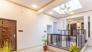 A spacious hallway with a tiled floor, a wooden door, and potted plants. - Lake N Hill View (Udaipur)