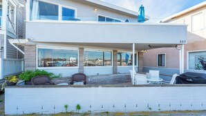 Ein modernes, zweistöckiges Haus mit überdachter Terrasse, Sitzgelegenheiten im Freien und Blick auf die Stadt.