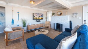 Ein modernes Wohnzimmer mit einer Couch, einem Couchtisch, einem Fernseher, einem Kamin und einer Wand mit einem Gemälde und Wanddekoration.