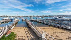 A marina with multiple boats docked, a wooden pier, and a clear sky. - Stylish Newport Condos w/ Dock Access, Walk to Balboa Fun Zone & Beach (Newport Beach)