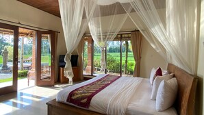 A spacious bedroom with a large bed, a wooden headboard, and a canopy. - Hening Suite Ubud (Tegallalang)