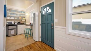 A compact kitchen with white cabinets, a teal door, and a window overlooking the street.