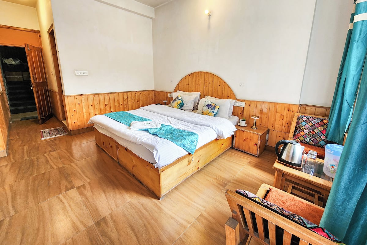 Un dormitorio con paneles de madera, una cama, una mesita de noche y una silla.