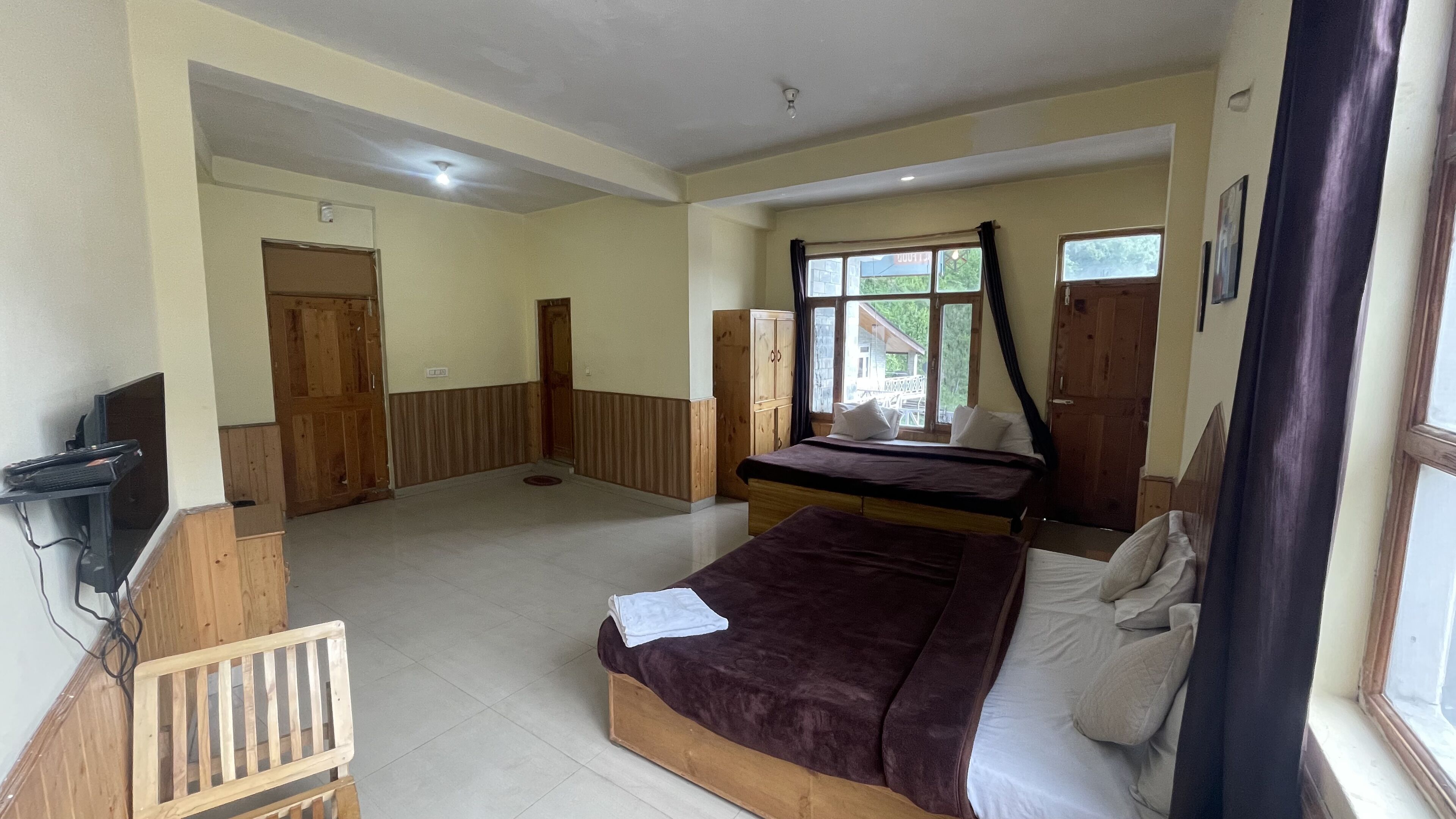 A bedroom with a bed, a desk with a computer, a wardrobe, and a window with curtains.