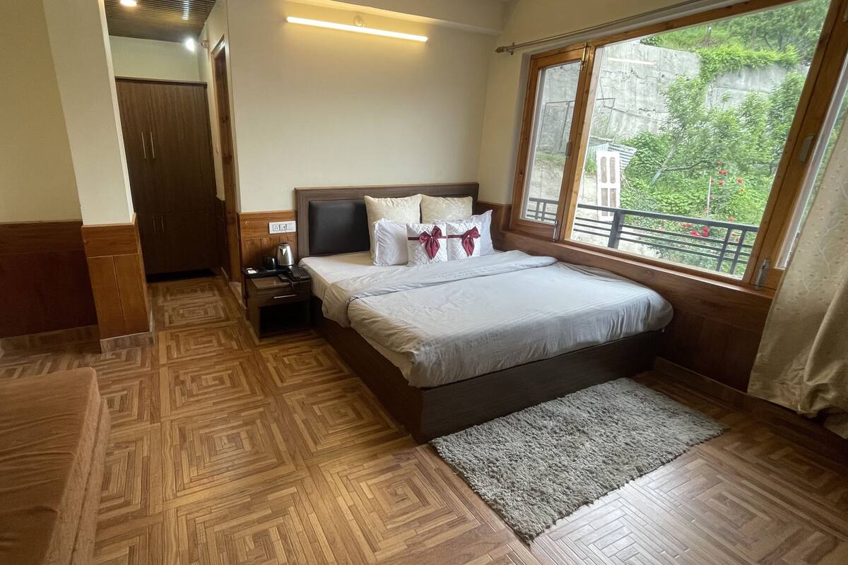 Un dormitorio con cama, mesita de noche y ventana con vistas a la vegetación.
