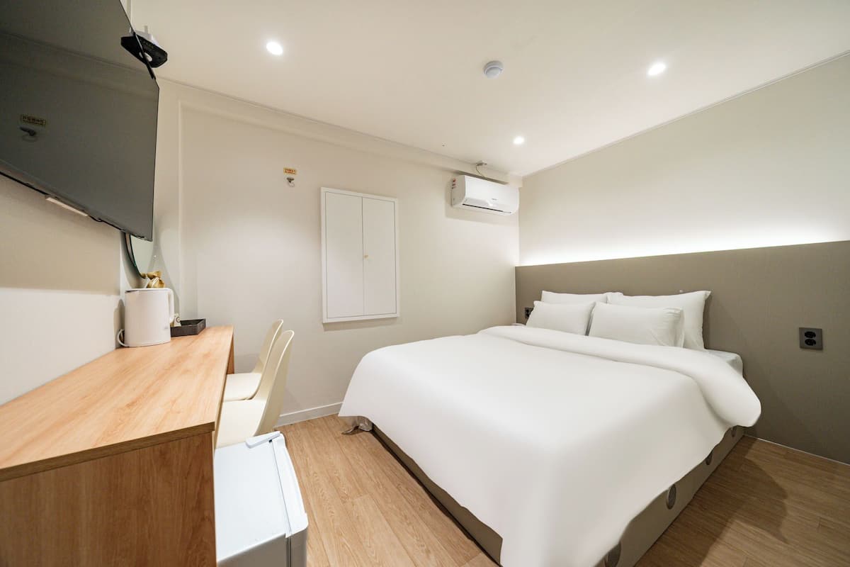 A modern hotel room with a bed, a desk, and a chair.