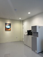 Una cocina limpia y moderna con refrigerador, microondas y cafetera.