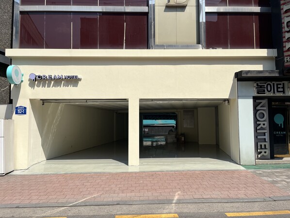 A hotel with a sign reading "CREAM HOTEL" and a parking garage entrance. - Cream Hotel (Guri)