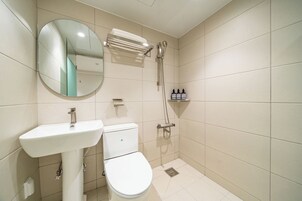 Un baño con lavamanos, inodoro, espejo y ducha.
