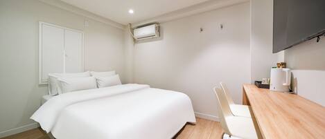 A hotel room with a bed, a desk, a chair, a flat-screen TV, and an air conditioning unit.