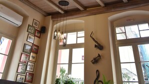 A room with wooden beams, hanging pendant lights, framed pictures on the wall, and a saxophone.