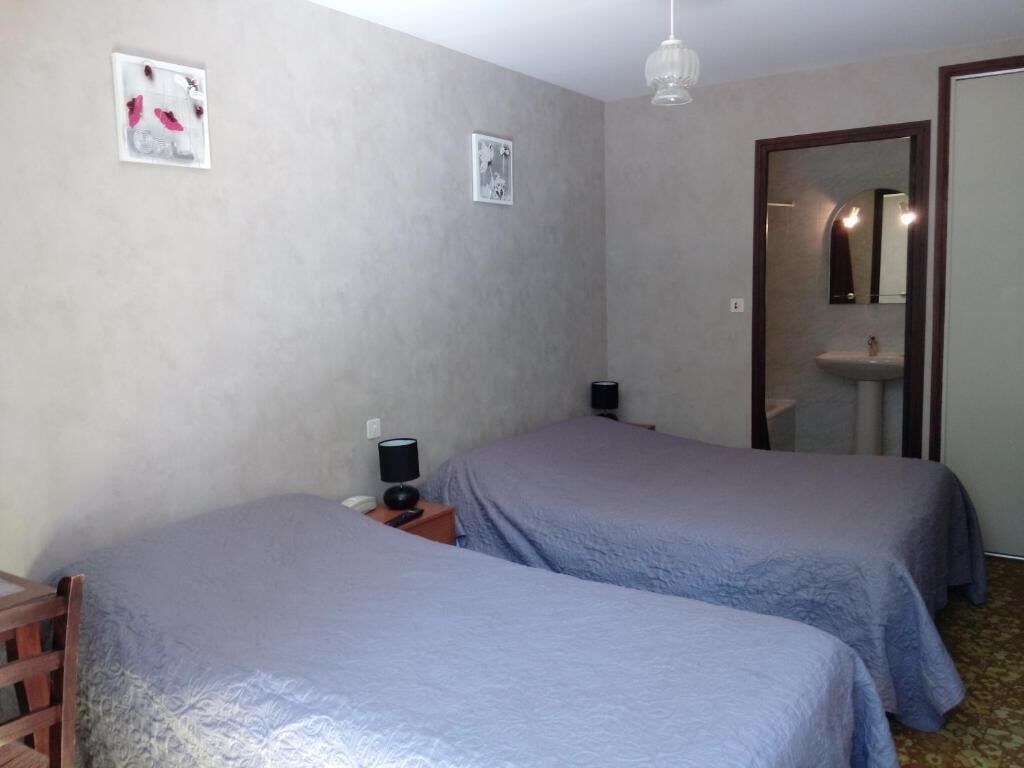 Una habitación de hotel con dos camas, una mesita de noche, una lámpara, un espejo y un lavabo.