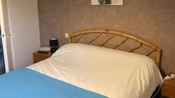 A bedroom with a bed, a nightstand, a lamp, and a wall-mounted picture.