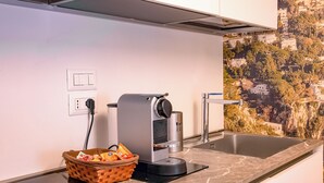 A kitchen with a coffee machine, a basket of snacks, and a sink. - CapriGetaway - Domus Le Botteghe (Capri)