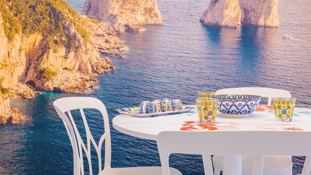 A table with a white tablecloth, a white chair, and a table setting with a plate, a bowl, and a glass. - CapriGetaway - Domus Le Botteghe (Capri)