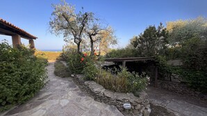 Un sendero de piedra que conduce a una estructura de madera rústica con vista al mar.
