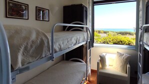 Un dormitorio con literas, una mesita pequeña y una ventana que da a zonas verdes y un cuerpo de agua.