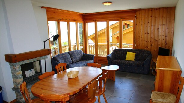 A cozy room with a wooden dining table, chairs, a sofa, and a fireplace. - Alluring apartment in Les Agettes (Les Agettes)