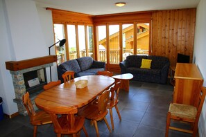 A cozy room with a wooden dining table, chairs, a sofa, and a fireplace. - Alluring apartment in Les Agettes (Les Agettes)