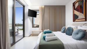 A modern hotel room with a large bed, a flat-screen TV, a balcony with a view, and a contemporary painting on the wall.