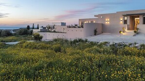 A modern house with a flat roof, a large patio, and a view of the sea.