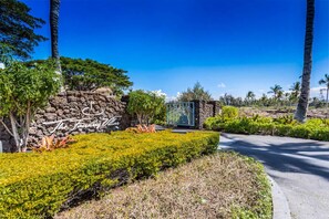A landscaped area with a stone wall, a sign reading 'The Fancy Villa,' and a gated entrance.