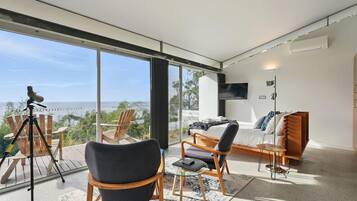 Una sala moderna con un ventanal que ofrece vistas panorámicas, un telescopio en una terraza y una zona de estar acogedora con un sofá y sillones.
