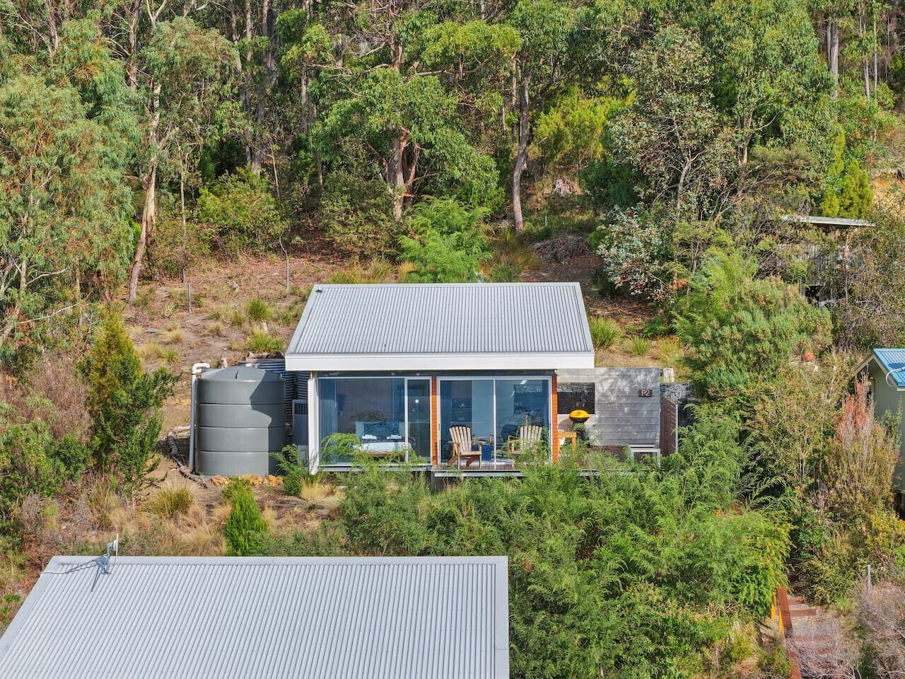 A modern house with a flat roof, large windows, and a patio with outdoor furniture.