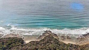 Un paysage côtier avec une plage, des affleurements rocheux et l’océan.