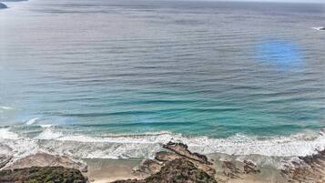 Paisaje costero con una playa, afloramientos rocosos y el océano.