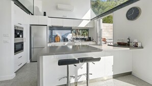 Een moderne keuken met witte kasten, een roestvrijstalen koelkast, een inbouwoven en een groot eiland met barkrukken.