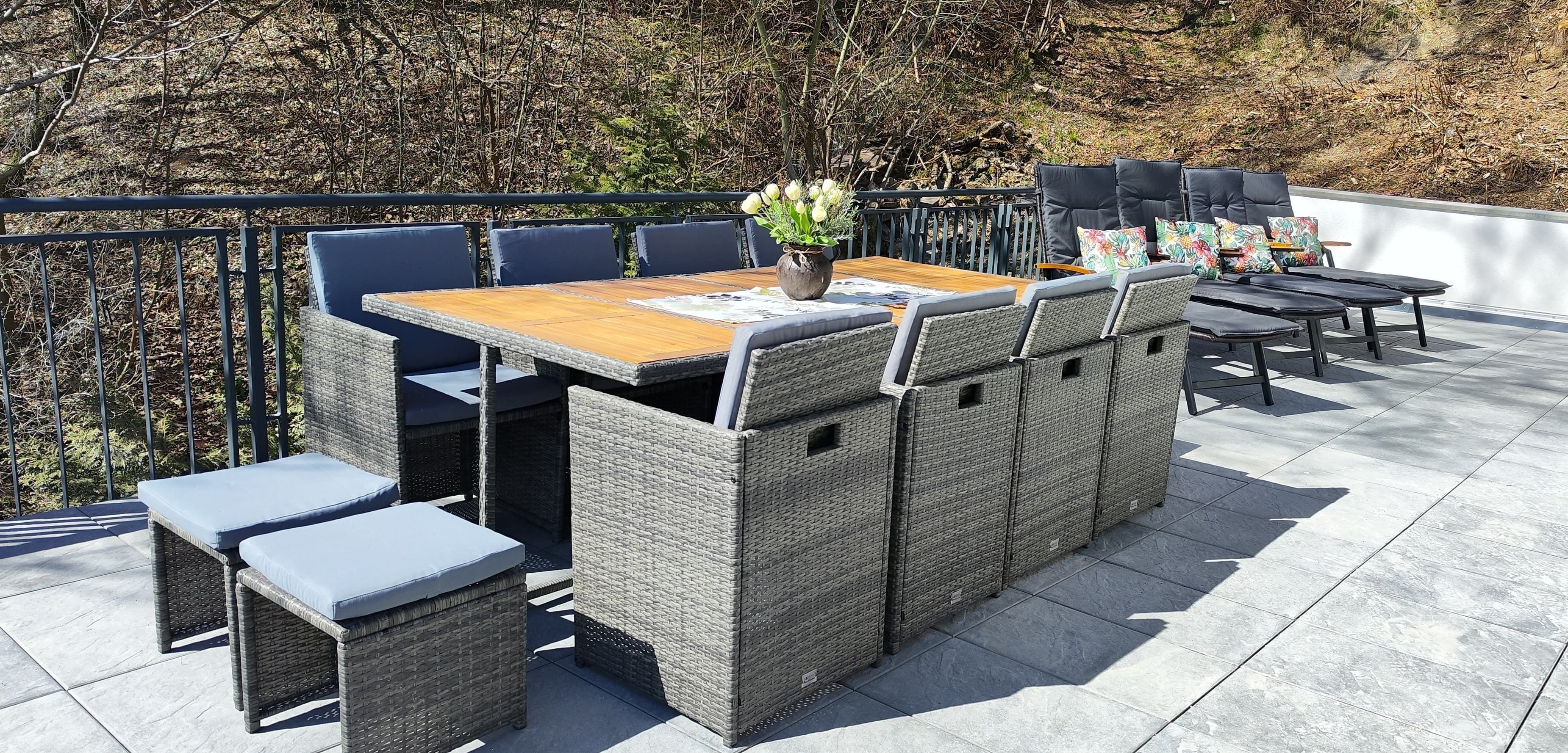 An outdoor patio with a wooden table, wicker chairs, and a cushioned bench.