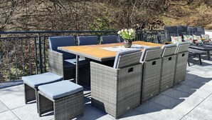 An outdoor patio with a wooden table, wicker chairs, and a cushioned bench. - Chalet on the Diemelsee with lake view, sun terrace and much more. Pet friendly (Diemelsee)
