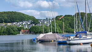 A lakeside view with boats, a tent, and a small house. - Chalet on the Diemelsee with lake view, sun terrace and much more. Pet friendly (Diemelsee)