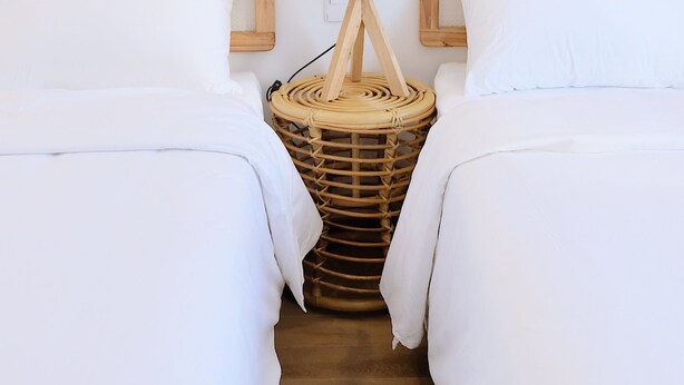 A bedroom with two beds, each with wooden headboards and white bedding. A wicker basket is placed between the beds. - NAMTO HOUSE PARK HAN MARKET 3A (Đà Nẵng)