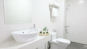 A modern bathroom with a white sink, toilet, and shower. There are small potted plants on the sink counter. - NAMTO HOUSE PARK HAN MARKET 3A (Đà Nẵng)