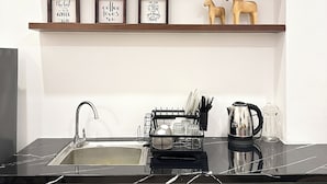 A kitchen with a black countertop, a sink, and a dish rack. There are three framed signs on the wall above the countertop. - NAMTO HOUSE PARK HAN MARKET 3A (Đà Nẵng)