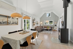 A spacious living area with a dining table, chairs, a sofa, a fireplace, and a large window.