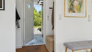 A hallway with a door leading to an outdoor area, a bench, and a framed artwork on the wall. - Cozy holiday home in scenic Rågeleje (Vejby)