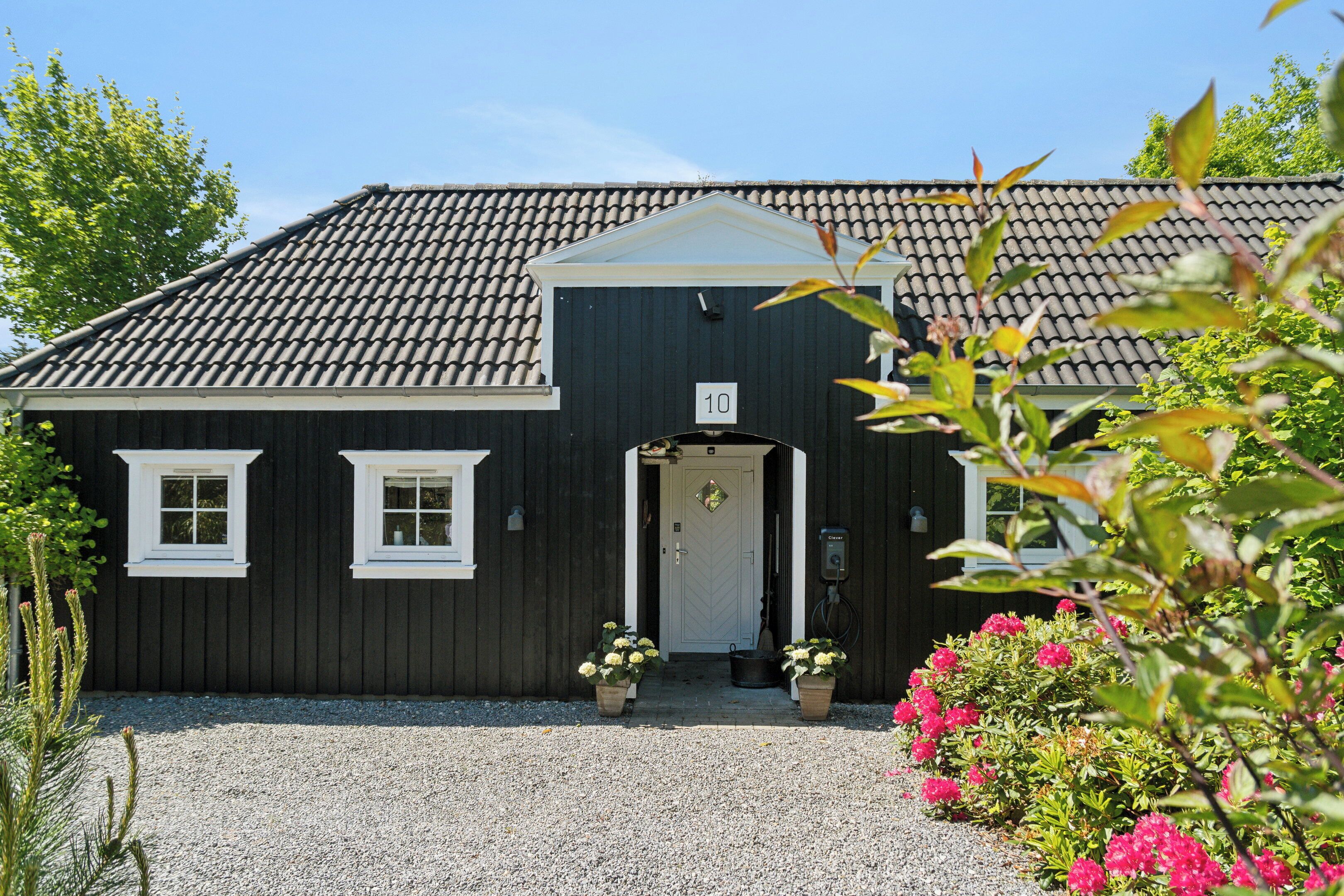A black building with a tiled roof, a number '10' sign, and a gravel driveway.