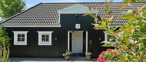 A black building with a tiled roof, a number '10' sign, and a gravel driveway.