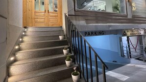 A staircase with potted plants, a wooden door, and a sign indicating a parking area. - Moti Mahal Inn (Haldwani)