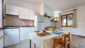 Eine kleine Küche mit Geschirrspüler, Kühlschrank und einem Esstisch, gedeckt mit Frühstücksartikeln.