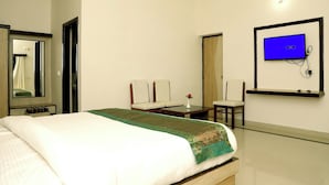 A hotel room with a bed, a desk, a chair, a television, and a mirror. - Hotel The Golden Bird (Agra)