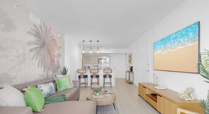 A modern living room with a sofa, coffee table, and a painting of a beach.