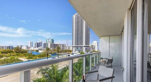 A balcony with a city view, a table with chairs, and a railing. - Amazing Apt w/ Balcony + Gym & Amazing Pool (Hallandale Beach)