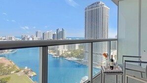 A balcony with a city view, a table with a vase, and a bottle. - Chic Studio with Balcony Views & Pool Access (Hallandale Beach)